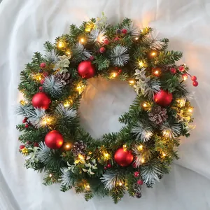 Christmas rattan wreath with red berries, pine cones and warm LED lights on white fabric