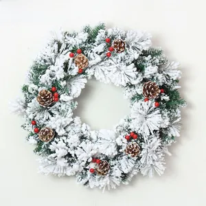 Close-up of frosted Christmas wreath with pine cones, red berries and snow flocking
