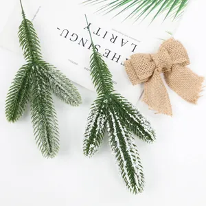 Detail of green and frosted pine needles with rustic burlap bow for holiday decor