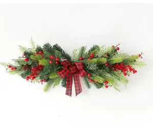 Detailed view of Christmas swag with red berries, pine needles and buffalo plaid bow