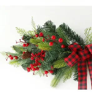 Close-up of Christmas wreath with red berries, pine cones and red-black plaid bow tie