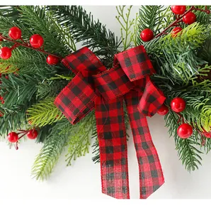 Close-up of Christmas wreath featuring green pine needles, red berries, and buffalo plaid bow