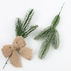 Close-up of frosted artificial pine needles with a rustic burlap bow for holiday decor