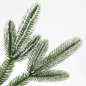 Macro shot of artificial green pine needles with realistic white frosted snow texture