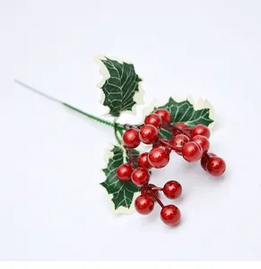 Detalle de bayas de acebo rojo artificiales con hojas verdes para decoración navideña