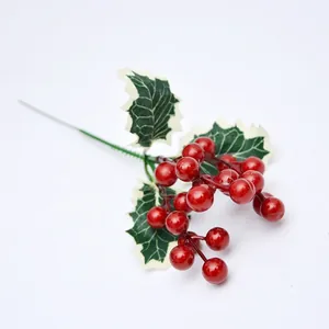 Ramas de bayas rojas de Navidad artificiales con hojas verdes en un fondo blanco