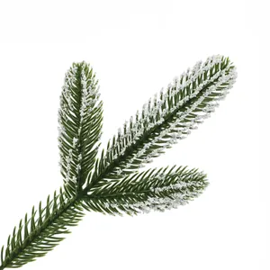 Detail of green artificial pine branches with three-forked structure and white flocked snow