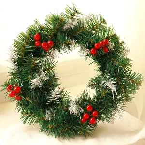Close-up of Christmas wreath with green pine needles, red berries and silver snow frost