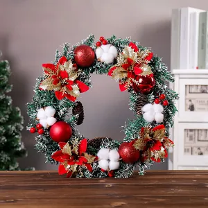 Detail van kerstkrans met rode ornamenten, kerststerren, dennenappels en zachte katoen