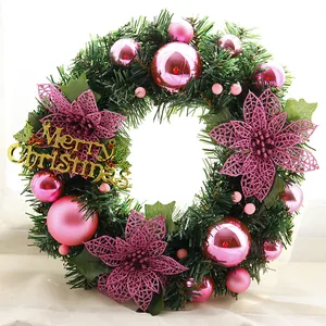 Close-up of pink poinsettia flowers and Christmas balls on flocked green pine wreath