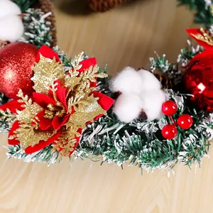 Detail van kerstkrans met rode kerstster, katoen, bessen en besneeuwde dennennaalden