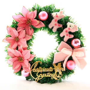 Details von rosa Weihnachtssternen und Rentierfiguren auf einem grünen Türkranz