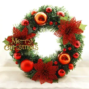 Close-up of a Christmas wreath with red flowers and a gold Merry Christmas sign