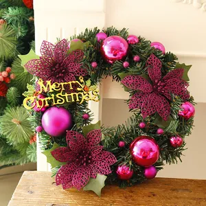 Close-up of a Christmas wreath with pine needles, pink baubles, and Merry Christmas sign