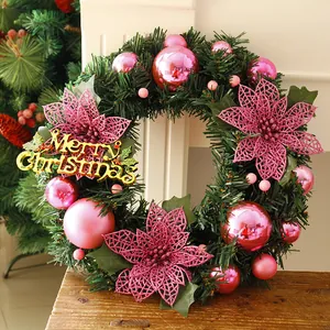 Detailed view of a Christmas wreath with pink ornaments and golden Merry Christmas sign