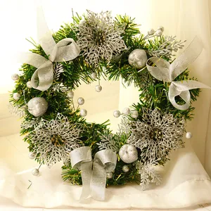 Close-up of green and silver Christmas wreath with berries, ribbon bows and glitter flowers
