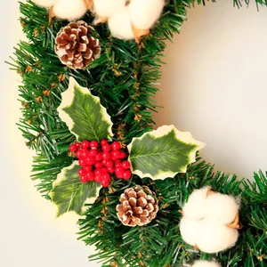 Weihnachtskranz mit grünen Kiefernnadeln, roten Beeren, Zapfen und Baumwollblüten
