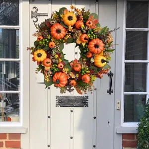 Autumn harvest wreath with golden pumpkins and berries on light gray wooden door