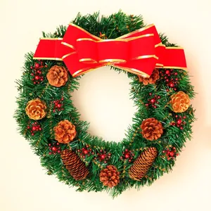 Green Christmas wreath with a red bow, pine cones, and red berries on a cream background