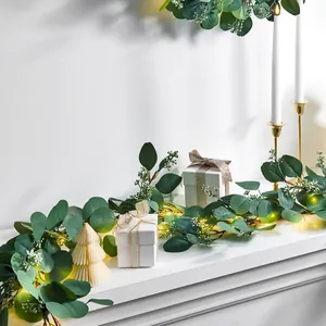 Artificial eucalyptus garland with warm LED lights on a fireplace for festive decor