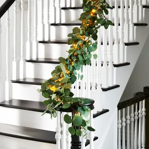 Artificial Christmas garland with LED lights and eucalyptus leaves on white stairs