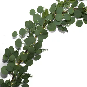 Detail of artificial eucalyptus garland with warm LED lights and white floral accents