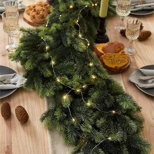 Christmas pine garland with warm white LED lights on a rustic wooden dining table decor