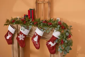 Weihnachtsdeko mit Rentier-Samtstrümpfen, künstlichen Tannenzweigen und roten Beeren