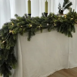 Detail of soft PVC Christmas pine garland with warm LED lights on a white tablecloth
