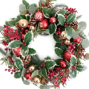 Detail eines Weihnachtskranzes mit roten Beeren, Zapfen und verschneiten Stechpalmen