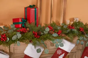 Detail der Weihnachtsgirlande mit Tannennadeln, roten Beeren und Zapfen auf dem Kaminims