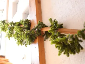 Detailed view of realistic green PE pine needle garland wrapped on wooden stairs