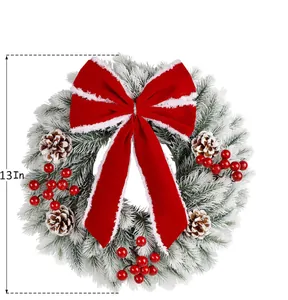 Detail of 13-inch snowy PE Christmas wreath with red velvet bow, pine cones and red berries