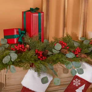 Weihnachtsgirlande mit roten Beeren, Zapfen und Nikolausstiefeln am Kaminholz