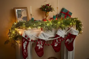 Detailed close-up of green pine garland with warm LED lights and red Christmas stockings