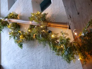 Close-up of flexible green PE cedar garland with warm white LED lights on a staircase