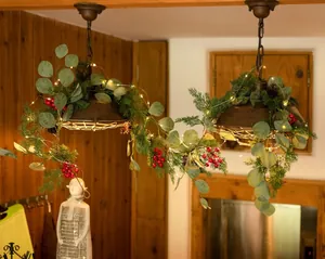 Detail der Weihnachtsguirlande mit Tannennadeln und warmen LED-Lichtern am Kronleuchter