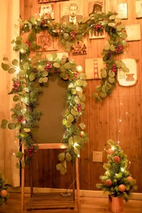 Detail der beleuchteten Weihnachtsgirlande mit roten Beeren, Tannennadeln und LED-Lichtern