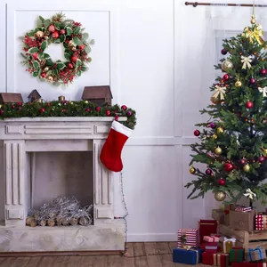 Weihnachtskranz mit roten Beeren, Zapfen und Ornamenten an einem gemütlichen Kamin