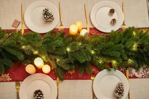 Close-up of artificial Christmas garland with warm LED lights and pine cones on a festive table