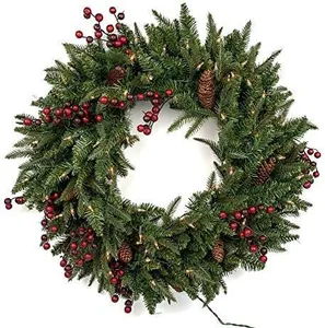 Detailansicht eines Weihnachtskranzes mit Tannennadeln, roten Beeren und warmen LED