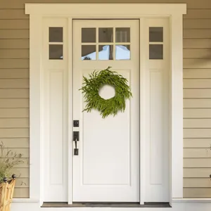 Lush green artificial cedar pine needle wreath hanging on a white wooden front door