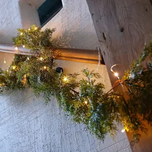 Artificial PE Christmas garland with warm LED lights wrapped on a rustic wooden beam