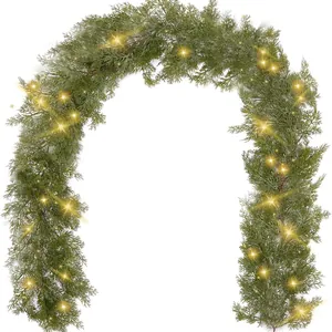 Lush green artificial Christmas garland with glowing warm LED lights on white background