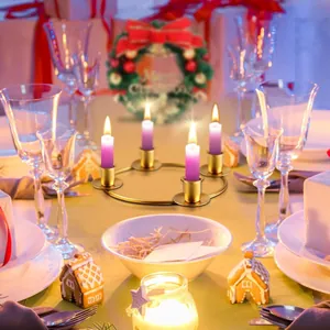 Moderne gouden metalen kerstkandelaar met vier paarse stompkaarsen op een feestelijke tafel