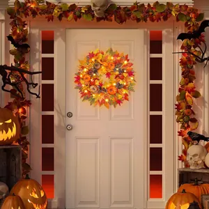 Close-up of lighted autumn wreath with maple leaves and pumpkins on a white front door