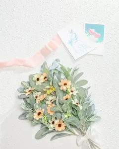 Vue détaillée du bouquet de marguerites artificielles avec feuilles de cinéraire et ruban