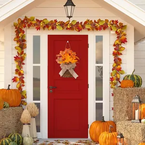 Close-up of autumn harvest wreath with sunflowers and berries hanging on a red front door