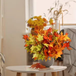 Artificial maple leaf branches in a gray ceramic vase for autumn home table decor
