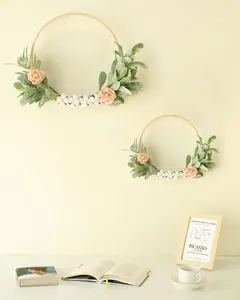 Détail de deux couronnes d'oreilles d'agneau avec roses roses et baies sur anneaux bois